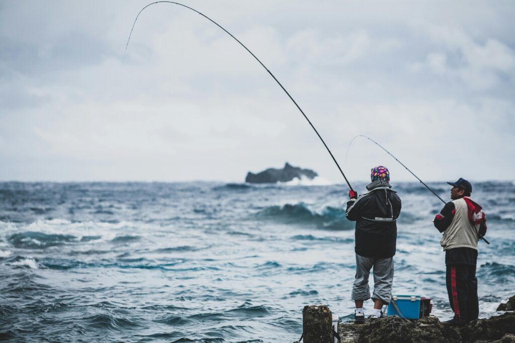 Two men fishing by the sea in Taiwan, capturing the essence of patience and recreation.
