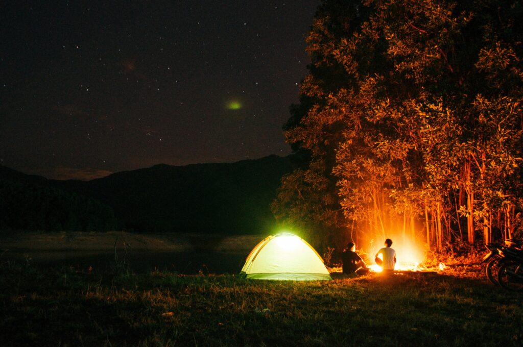 A tranquil camping scene at night with a tent and campfire under a starry sky in Chư Sê, Vietnam.